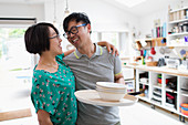 Couple hugging, doing dishes in kitchen