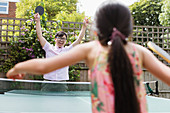 Exuberant father and daughter playing table tennis