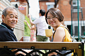 Daughter and senior father drinking tea on bench