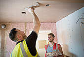 Construction workers plastering ceiling