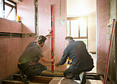 Construction workers using level tool