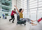 Couple running with luggage cart in airport