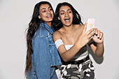 Teenage twin sisters taking selfie