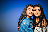 Portrait teenage twin sisters hugging