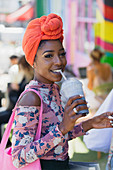Smiling young woman in headscarf drinking smoothie