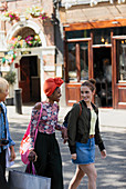 Young women friends shopping, walking on street