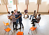 Men hugging and clapping in group therapy