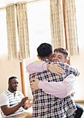 Men hugging in group therapy