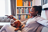 Young woman and dog relaxing, watching TV