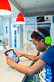 Boy with headphones and digital tablet playing video game