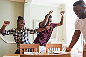 Playful teenage brother and sister dancing in dining room