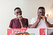 Teenage brothers eating pizza