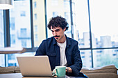 Focused man working at laptop in urban apartment