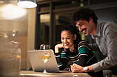 Happy couple using laptop and drinking white wine