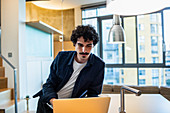 Focused man working at laptop in apartment kitchen