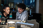 Smiling couple using laptop and drinking white wine