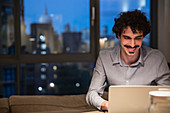 Man using laptop in urban apartment at night
