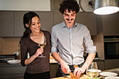 Happy couple preparing dinner and drinking white wine