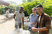 Portrait male friends enjoying backyard barbecue