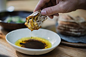 Hand dipping bread in olive oil and balsamic vinegar