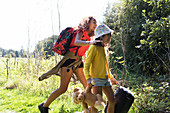 Sisters camping, carrying suitcase and teddy bear in field