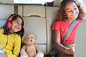 Sisters and teddy bear riding in back seat of car