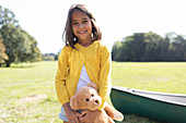 Portrait smiling, cute girl with teddy bear in field