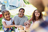 Father serving barbecue hamburgers to eager family