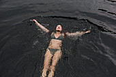 Serene woman in bikini floating in lake