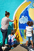 Mother and daughter volunteers painting mural on wall