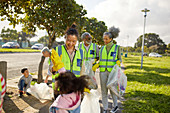 Happy volunteers high-fiving, cleaning up litter in park