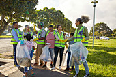 Happy volunteers celebrating, cleaning litter from park