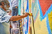 Senior man painting mural on wall