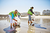 Female volunteers picking up litter on wet sand beach