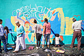 Community volunteers painting vibrant mural on wall
