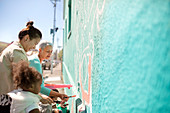 Female volunteers painting mural on wall