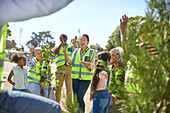 Enthusiastic volunteers cheering, planting trees at park