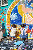 Girls painting vibrant mural on wall