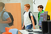 Junior high boy students walking in library