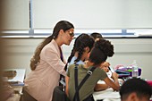 Teacher helping school students at desk