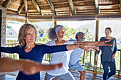 Yoga class practicing warrior 2 pose in hut