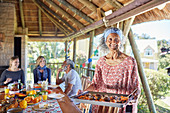 Portrait senior woman serving food to guests in hut