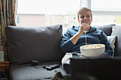 Young woman eating popcorn on sofa