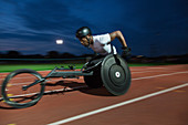 Determined paraplegic athlete in wheelchair race at night