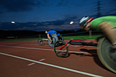 Paraplegic athletes in wheelchair race at night