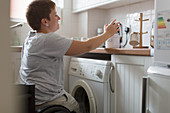 Young woman in wheelchair preparing tea