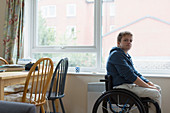 Portrait woman sitting in wheelchair at window