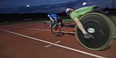 Paraplegic athletes in wheelchair race at night