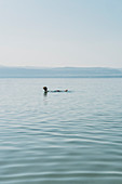 Man floating, swimming in Dead Sea, Jordan