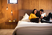 Couple reading book and using digital tablet in bed